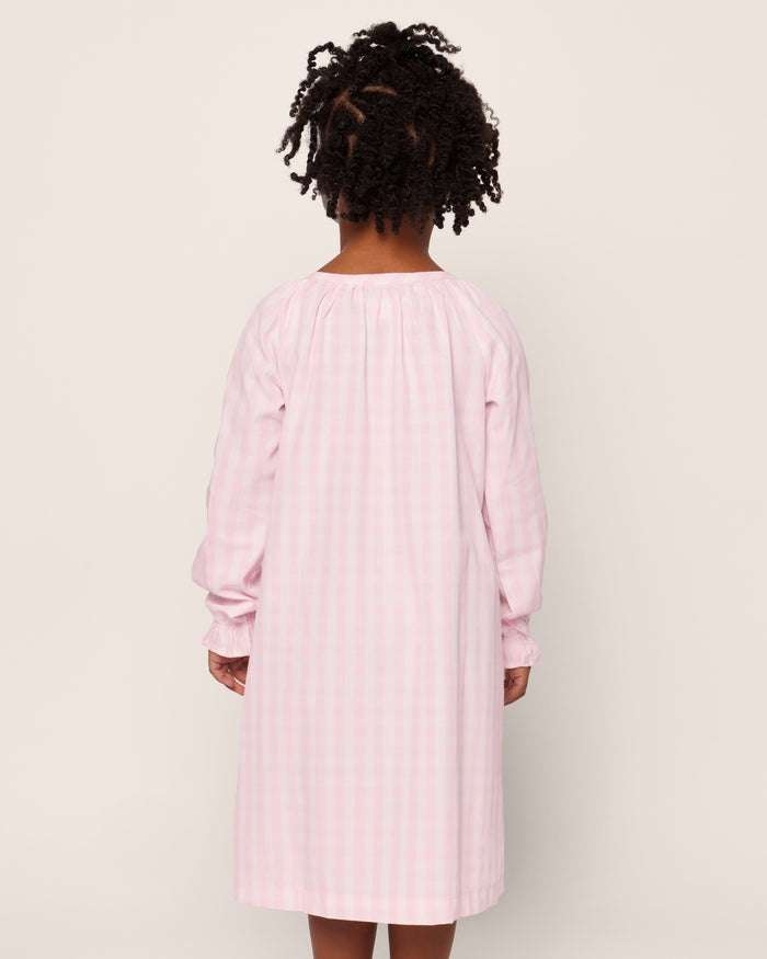 The Petite Plume Girls Twill Delphine Nightgown in Pink Gingham features long sleeves, a rounded neckline with a small keyhole opening, and ruffled cuffs, made from flame-retardant fabric.