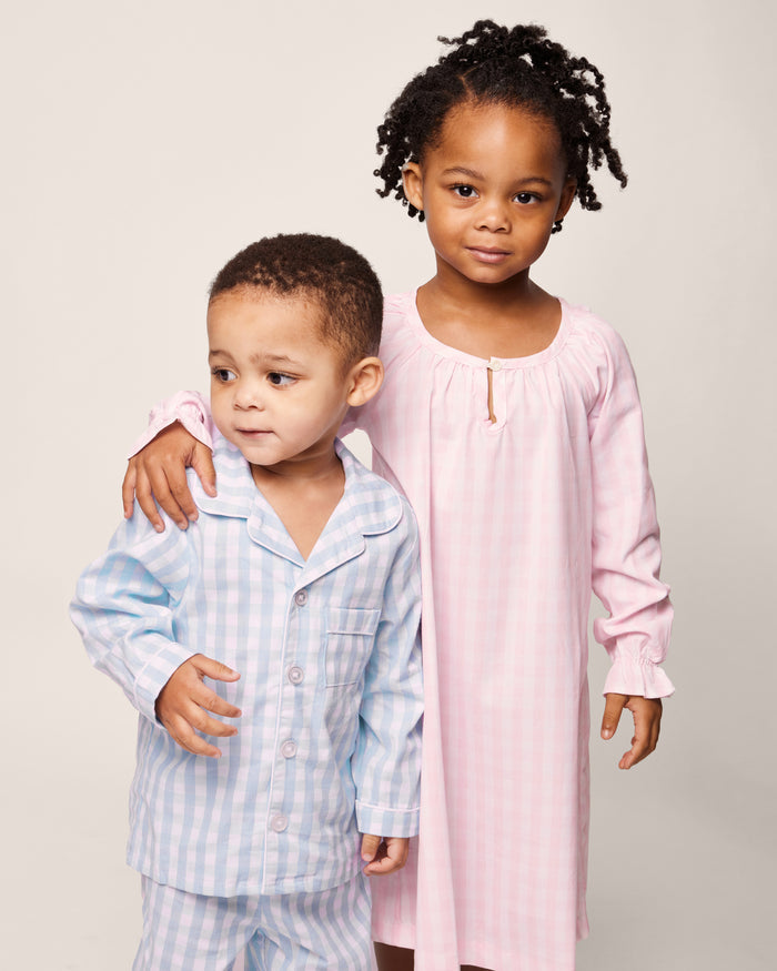 The Petite Plume Girls Twill Delphine Nightgown in Pink Gingham features long sleeves, a rounded neckline with a small keyhole opening, and ruffled cuffs, made from flame-retardant fabric.