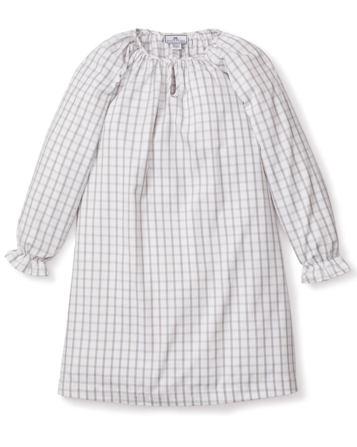 The Girls Twill Delphine Nightgown in Regent Tattersall by Petite Plume is a knee-length, long-sleeved dress with a gray and white checkered pattern. Made from yarn-dyed cotton, it has a round neckline with a keyhole opening and ruffled cuffs. The soft, lightweight fabric is ideal for casual wear.