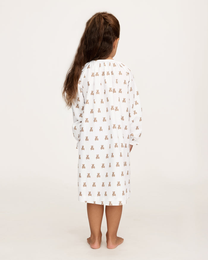 The Girl's Twill Delphine Nightgown in Teddy Tales features long sleeves, a white fabric with an all-over brown teddy bear print, a gathered neckline, ruffled cuffs, and a button closure at the collar.