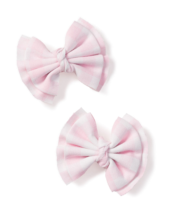 A duo of charming pink gingham twill hair bows from Petite Plume, featuring pleated designs, elegantly placed side by side against a crisp white background.