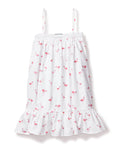 The Girls Twill Lily Nightgown in Flamingos by Petite Plume blends summer charm and cotton comfort. This white sundress features thin straps, a playful pink flamingo pattern, a ruffled hem, and a textured band near the neckline for a breezy yet cozy feel.