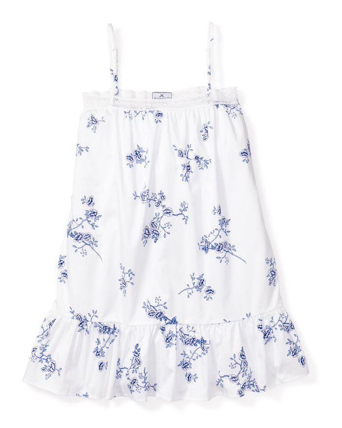 Girls Twill Lily Nightgown in Indigo Floral by Petite Plume is a white sleeveless dress with thin straps and a vintage lace nightgown style. It features blue floral print, lace trim along the neckline, and a ruffled hem.