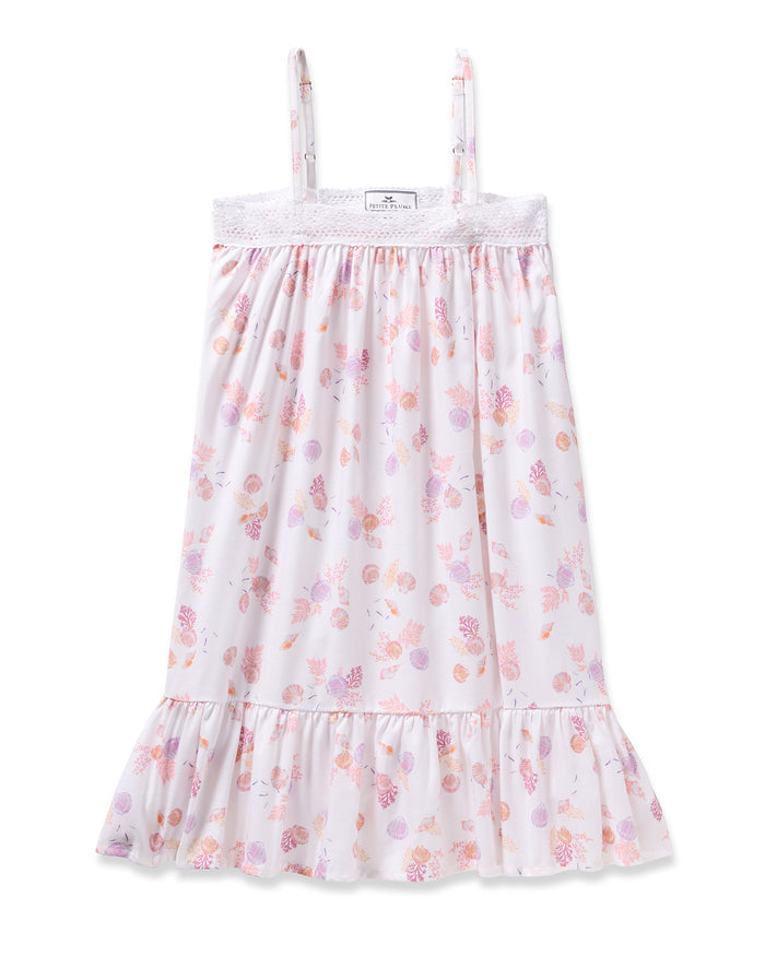 Enjoy the elegance of Petite Plumes Girls Twill Lily Nightgown in Seashell Splendor—a white sleeveless dress boasting pink and purple floral and fruit patterns, yarn-dyed cotton, a lacy trim top, and a ruffled hem for luxurious sleep.