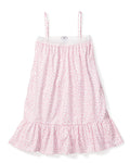 The Girls Twill Lily Nightgown in Sweethearts by Petite Plume is a luxurious sleeveless, knee-length sleepwear piece. It features thin straps, a pink heart pattern on a white background, and is crafted from yarn-dyed cotton with a textured upper section and ruffled bottom hem.
