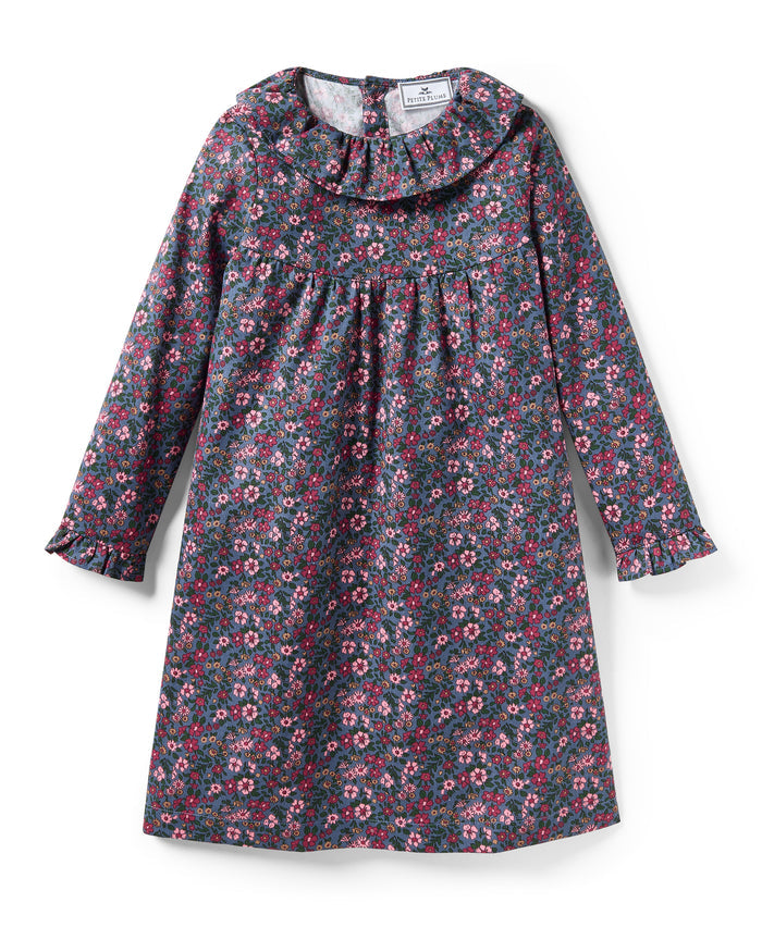 The Girl's Twill Scarlett Nightgown in Fleurs de Saison is a long-sleeved, knee-length dress with a ruffled collar and cuffs, featuring pink and white flowers with green leaves on a dark background.