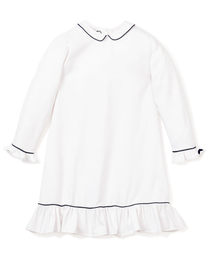 The Girls Twill Sophia Nightgown by Petite Plume is a white long-sleeve gown with navy piping on the Peter Pan collar and cuffs. Made from yarn-dyed cotton, it boasts ruffled cuffs and hem for an elegant touch, perfect for stylish sleepwear.