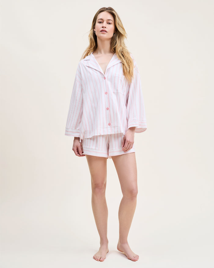 The Olivia Pima Short Set in Pink Stripe features a two-piece pajama set with white and pink vertical stripes, a long-sleeve button-up top with chest pocket, and matching drawstring shorts.