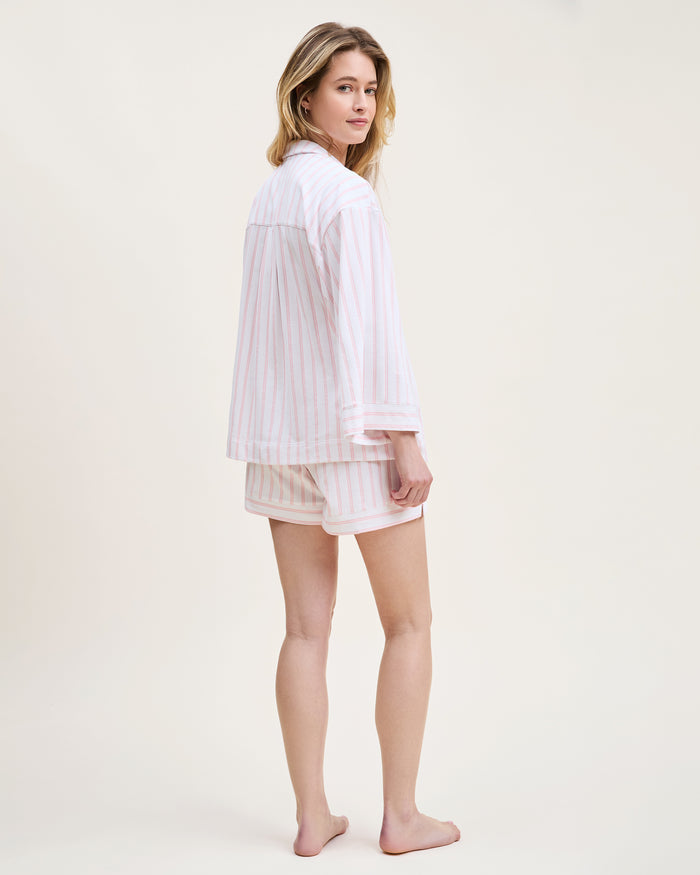The Olivia Pima Short Set in Pink Stripe features a two-piece pajama set with white and pink vertical stripes, a long-sleeve button-up top with chest pocket, and matching drawstring shorts.