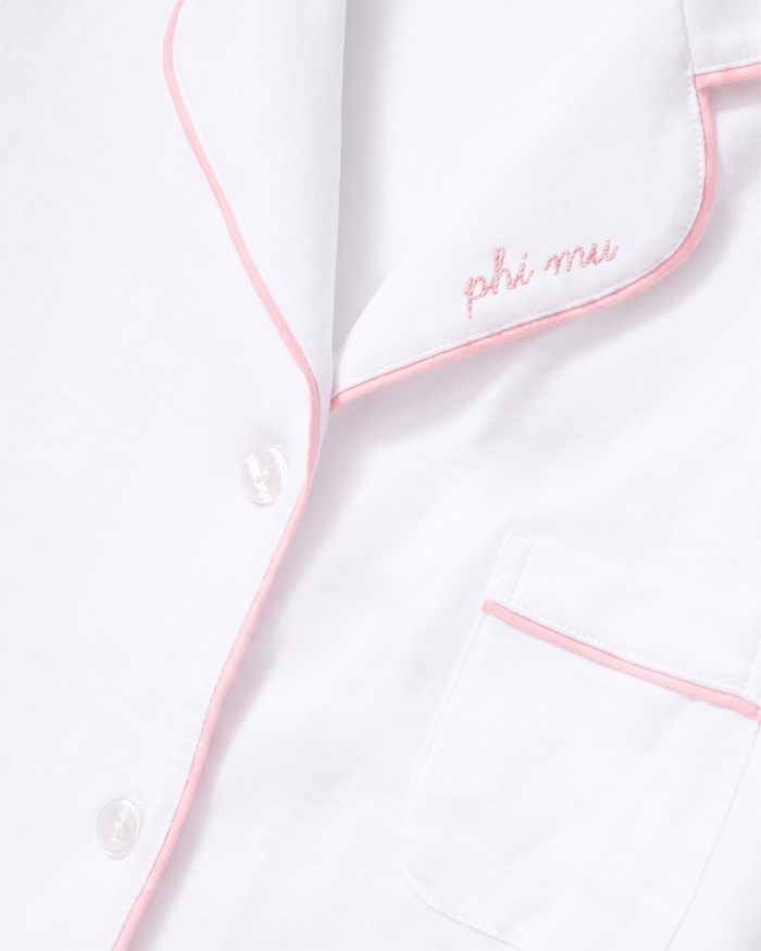 The Greek Embroidered Poppy Pima Short Set in White with Pink Piping features a white pajama shirt with pink piping trim, “Phi Mu” embroidered in pink script on the collar, a chest pocket, and white buttons.