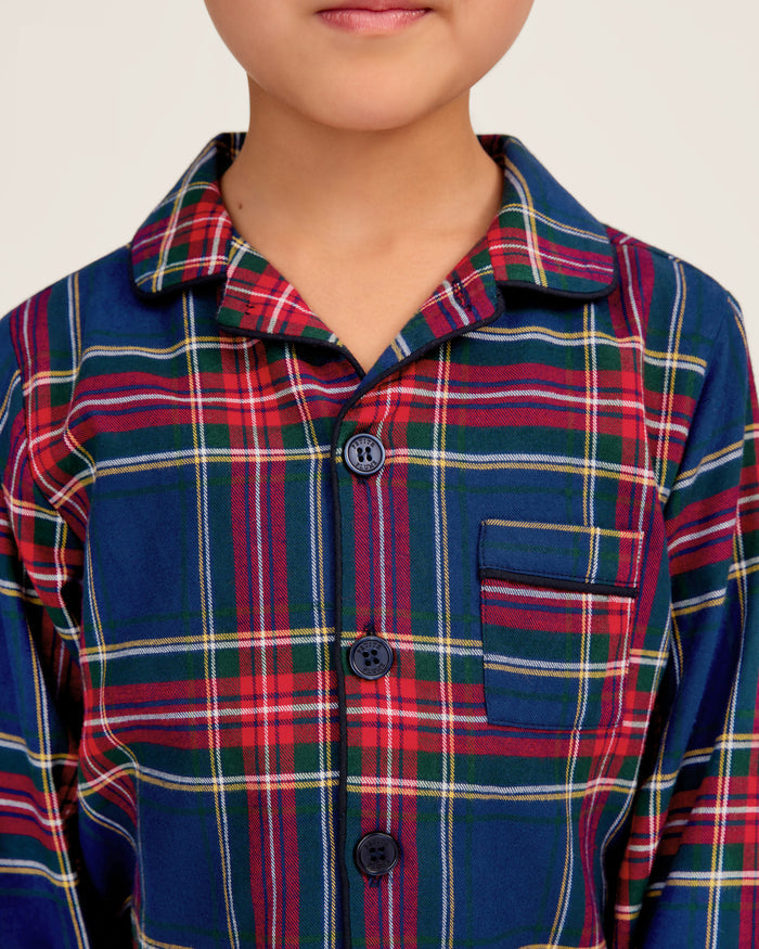Close-up of a lavish Kids Brushed Cotton Pajama Set in Windsor Tartan by Petite Plume, showcasing red, blue, green, and yellow intersecting stripes forming squares and rectangles. A visible button and seam complete this classic pajama look.