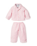 A person in a long-sleeved white shirt holds an adorable 18 baby doll with a light skin tone, dressed in Petite Plumes Kids Flannel Doll Pajamas in Pink, perfectly matching their own attire. Only the shoulder and one arm of the individual are visible.