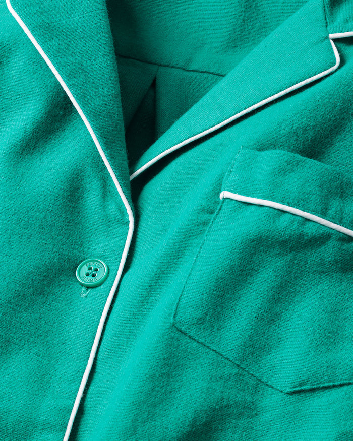 Close-up of Petite Plumes Kids Flannel Pajama Set in Forest Green, featuring white piping, button, and pocket. The soft material and bright color in a simple design make it eye-catching sleepwear for children.