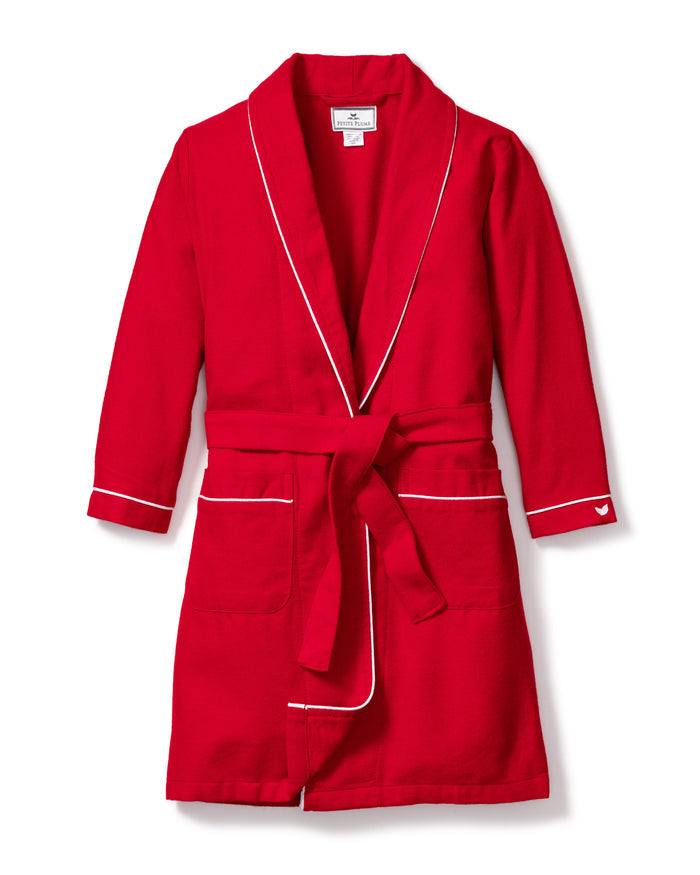 The Kids Flannel Robe in Red with White Piping by Petite Plume is made from chemical-free fabric. It includes a shawl collar, two front pockets, and a matching waist tie, designed as childrens sleepwear and showcased against a white background.