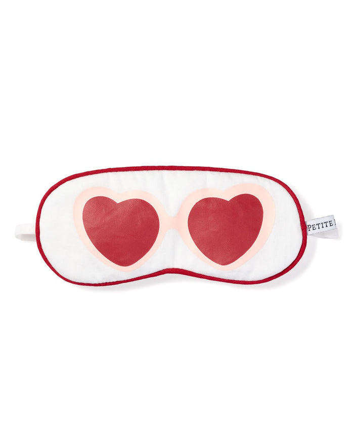 The Kids Maisonette Exclusive Je tadore Valentines Sleep Mask by Petite Plume is white with red trim and two red hearts outlined in pink, resembling sunglasses. PETITE is labeled on the right side to complement your luxurious sleepwear.