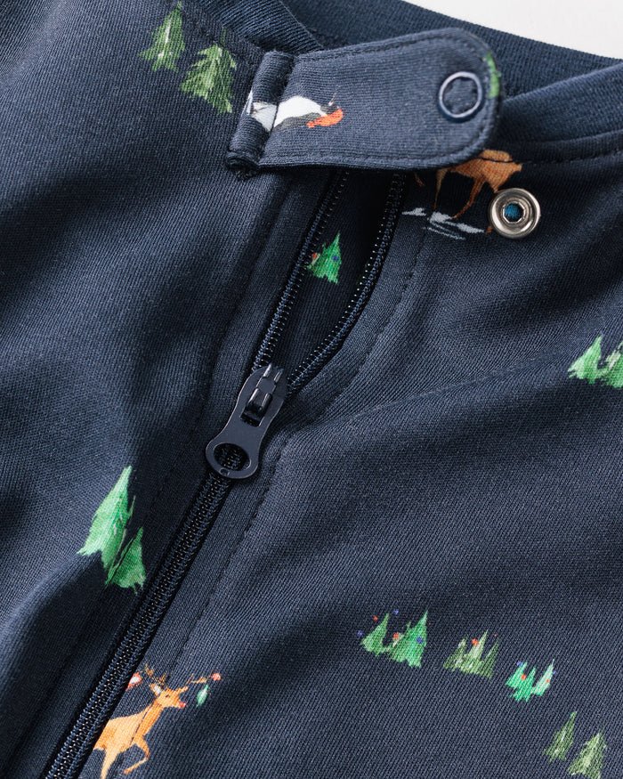 Close-up of the Kids Pima Snug Fit Pajama Set in Arctic Antics by Petite Plume, showcasing dark Pima cotton fabric with a zipper and button. It features festive tree and animal illustrations, including a red-nosed deer, embodying cozy holiday sleepwear.