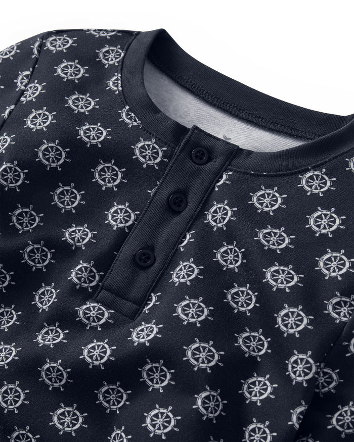 A close-up of the Kid’s Pima Snug Fit Pajama Set in Captain’s Compass, showcasing its navy blue fabric with a round collar, three buttons, and a repeating white ship wheel pattern.