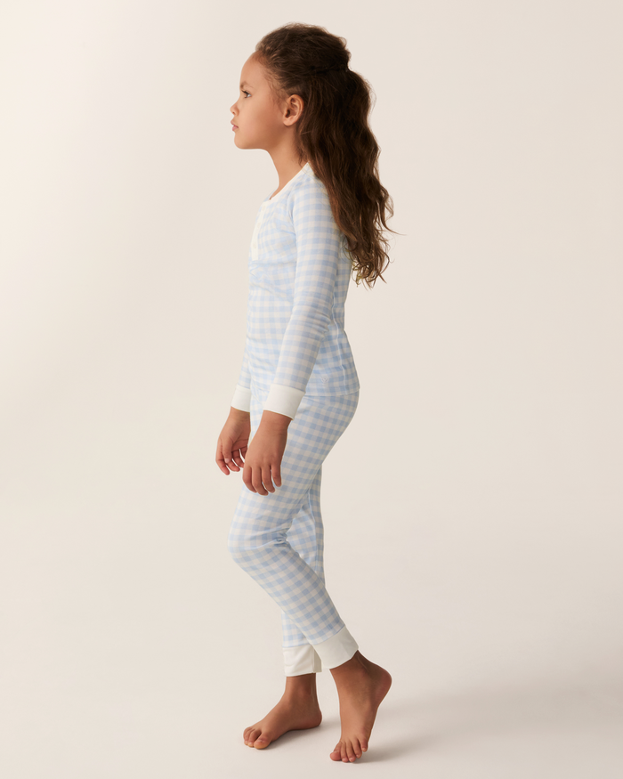 A young girl wearing the Kid’s Pima Snug Fit Pajama Set in Light Blue Gingham, featuring white cuffs, is shown in profile against a light background.