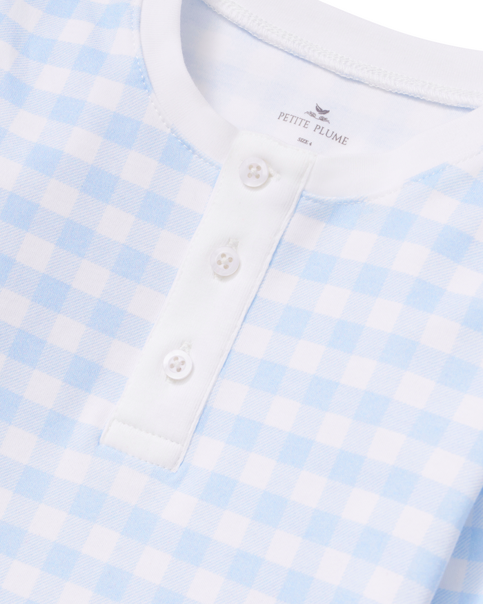 Close-up of the Kid’s Pima Snug Fit Pajama Set in Light Blue Gingham, featuring a blue and white gingham pattern, white buttons, and a white collar. The label inside reads PETITE PLUME.