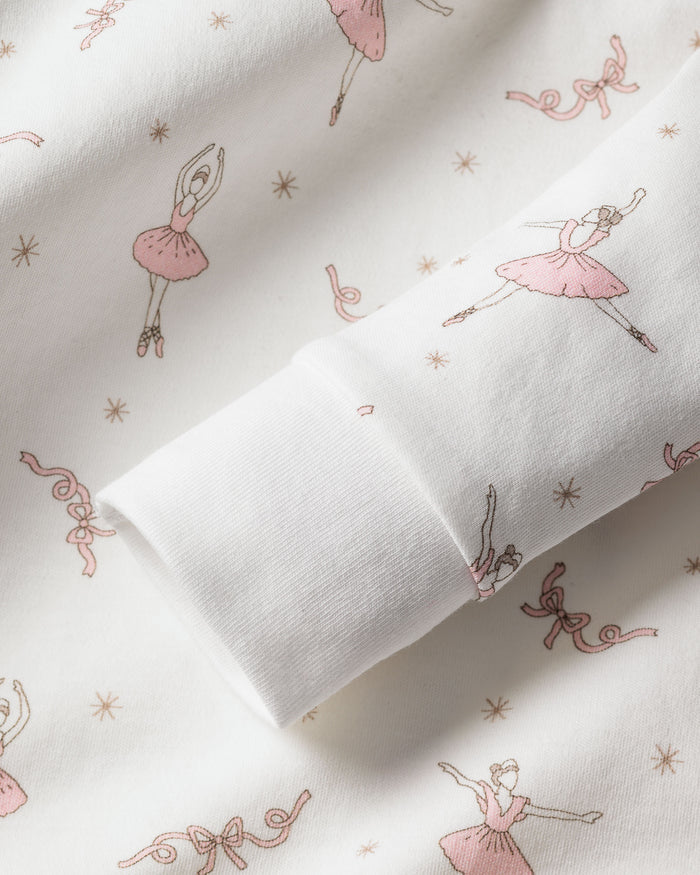 The Kids Pima Snug Fit Pajama Set in Sugar Plum Fairy by Petite Plume showcases soft Pima cotton adorned with charming pink ballerinas, small stars, and ribbons. The long sleeve top includes rolled-up sleeves to accentuate the delicate pattern.