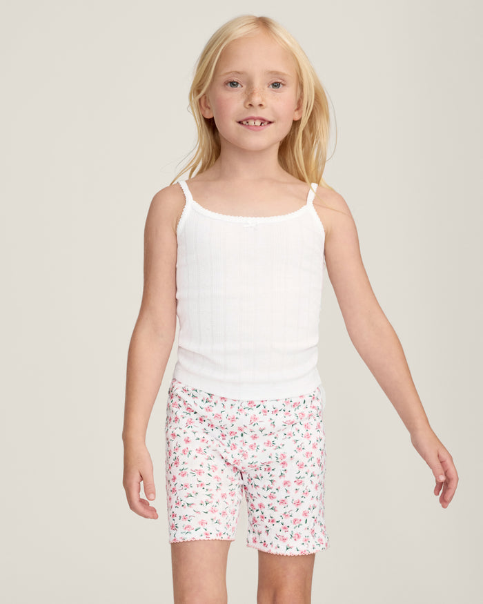 The Kid's Pointelle Cami Set of 2 in White & Pink Floral includes two sleeveless camisoles: one plain white with a bow and one white with a pink and green floral pattern. Both feature thin straps and lace trim.