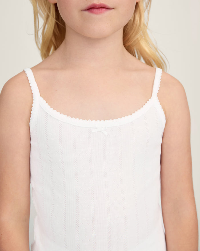 The Kid's Pointelle Cami Set of 2 in White & Pink Floral includes two sleeveless camisoles: one plain white with a bow and one white with a pink and green floral pattern. Both feature thin straps and lace trim.