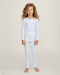A young child with long curly hair stands barefoot against a plain background, wearing the Kid's Pointelle Snug Fit Pajama Set in Blue Floral.