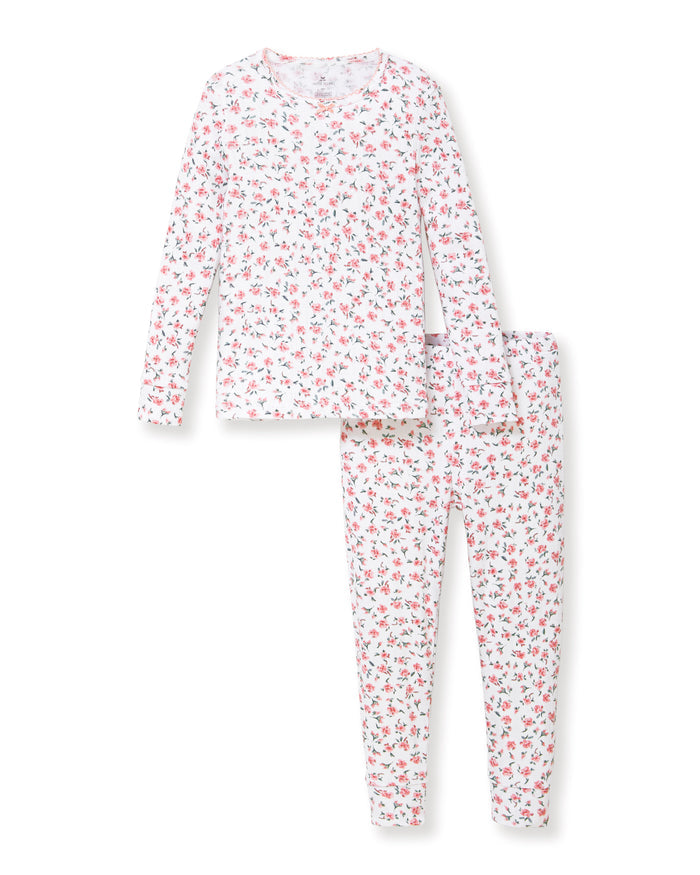 A young girl stands barefoot against a plain background, wearing the Kid's Pointelle Snug Fit Pajama Set in Pink Floral. She faces forward with a relaxed, neutral expression.
