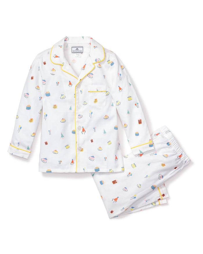 The Kids Twill Pajama Set in Birthday Wishes by Petite Plume is adorned with prints of small kitchen items like whisks, eggs, and pastries. This comfy classic set includes a top with a pocket and yellow piping, perfect for cozy relaxation.