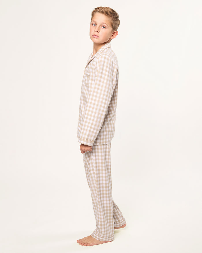 Kid's Twill Pajama Set in Camel Gingham features long sleeves, pants with an elastic waistband, and a button-up shirt with a collar and front pocket, all in a beige and white gingham check pattern.