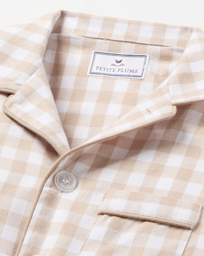 Kid's Twill Pajama Set in Camel Gingham features long sleeves, pants with an elastic waistband, and a button-up shirt with a collar and front pocket, all in a beige and white gingham check pattern.