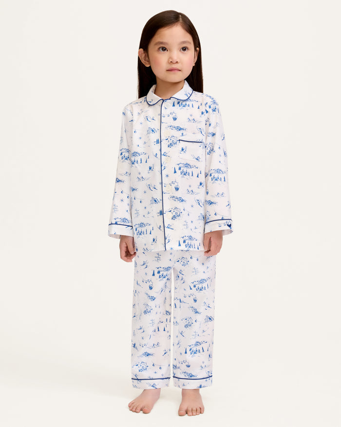 Kid's Twill Pajama Set in Chalet Toile, a white pajama set with blue piping and scenic print, includes a long-sleeve button-up top and matching pants, shown laid flat on a white background.