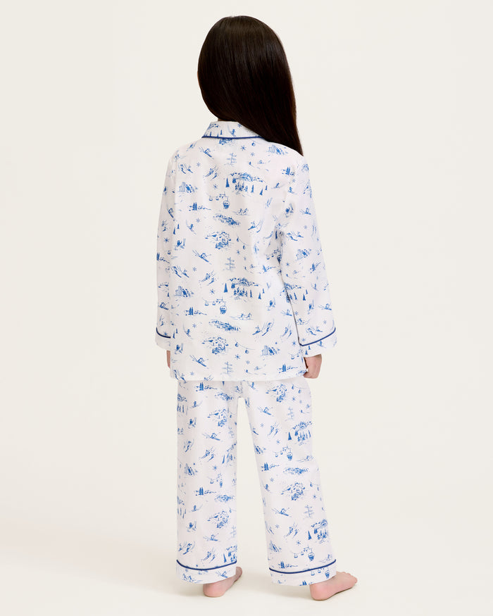Kid's Twill Pajama Set in Chalet Toile, a white pajama set with blue piping and scenic print, includes a long-sleeve button-up top and matching pants, shown laid flat on a white background.