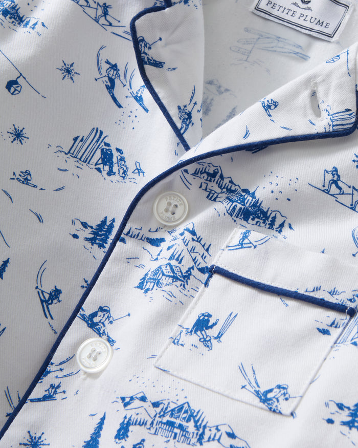 Kid's Twill Pajama Set in Chalet Toile, a white pajama set with blue piping and scenic print, includes a long-sleeve button-up top and matching pants, shown laid flat on a white background.