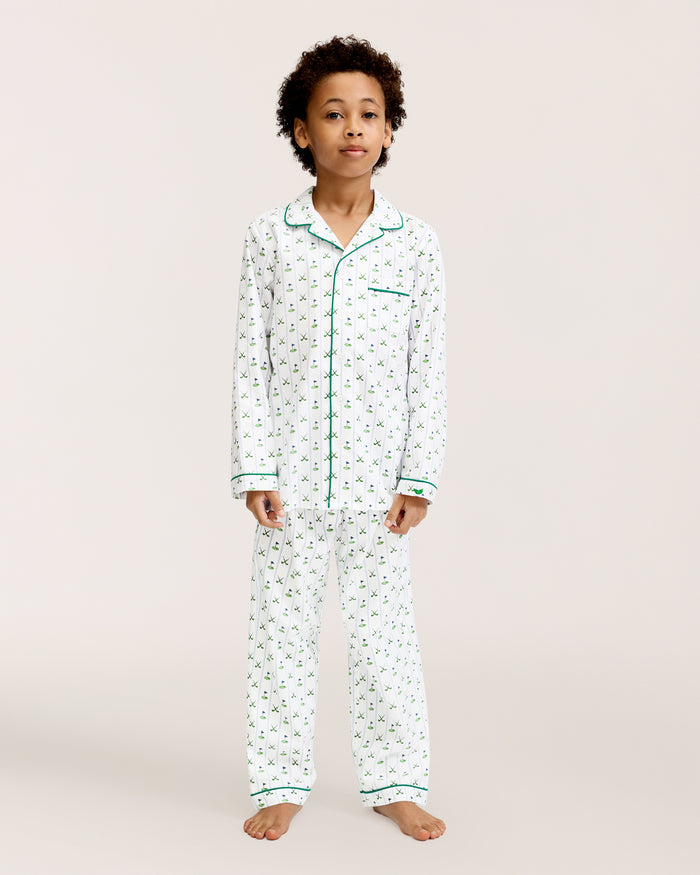 The Kid's Twill Pajama Set in Fairway Stripe features white pajamas with green piping, a tennis racket and green stripe pattern, a long-sleeve button-up top with a chest pocket, and matching long pants.