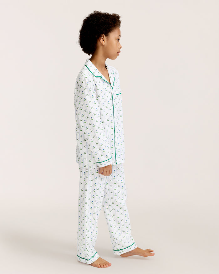 The Kid's Twill Pajama Set in Fairway Stripe features white pajamas with green piping, a tennis racket and green stripe pattern, a long-sleeve button-up top with a chest pocket, and matching long pants.