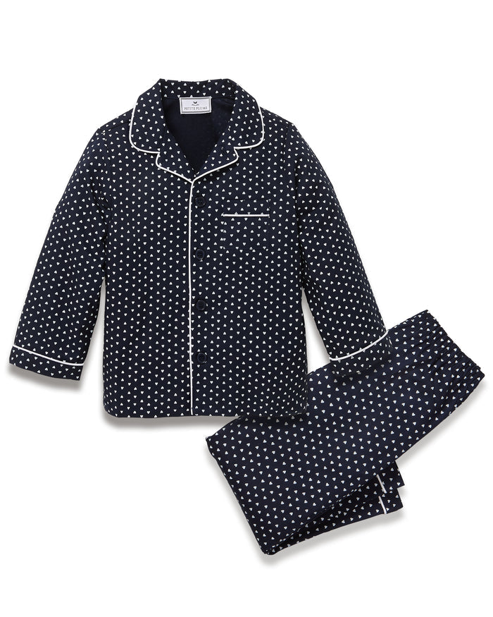 Kid's Twill Pajama Set in Midnight Hearts features navy blue pajamas with white heart prints, white piping, a long-sleeve button-up top with chest pocket, and matching pants.