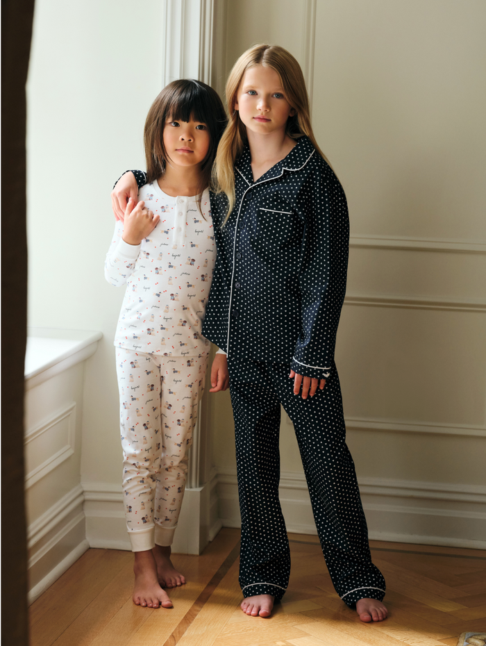 Kid's Twill Pajama Set in Midnight Hearts features navy blue pajamas with white heart prints, white piping, a long-sleeve button-up top with chest pocket, and matching pants.