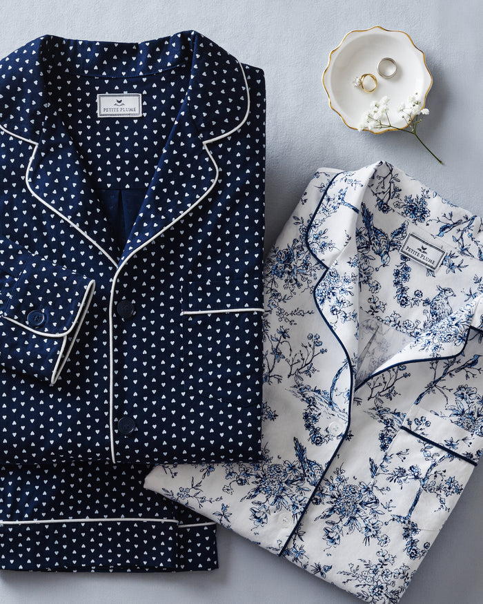 Kid's Twill Pajama Set in Midnight Hearts features navy blue pajamas with white heart prints, white piping, a long-sleeve button-up top with chest pocket, and matching pants.