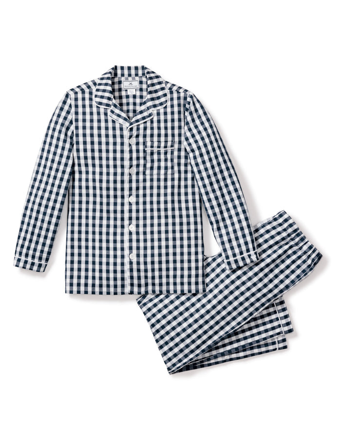 Experience luxury and classic style with Petite Plumes Kids Twill Pajama Set in Navy Gingham, showcasing a blue and white pattern. This set features a long-sleeved button-up top with a chest pocket and matching pants, all set on a white background.