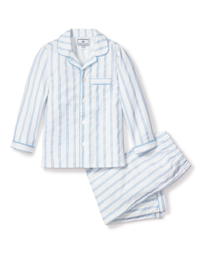 The Kids Twill Pajama Set in Periwinkle and White Stripe by Petite Plume features a button-up long-sleeve top with a collar and chest pocket, plus matching pants. Made from soft yarn-dyed cotton with periwinkle stripes on white.