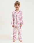 The Kid's Twill Pajama Set in Red Timeless Toile features a white base with red toile print, long-sleeve button-up top with front pocket, matching pants, and red piping accents.