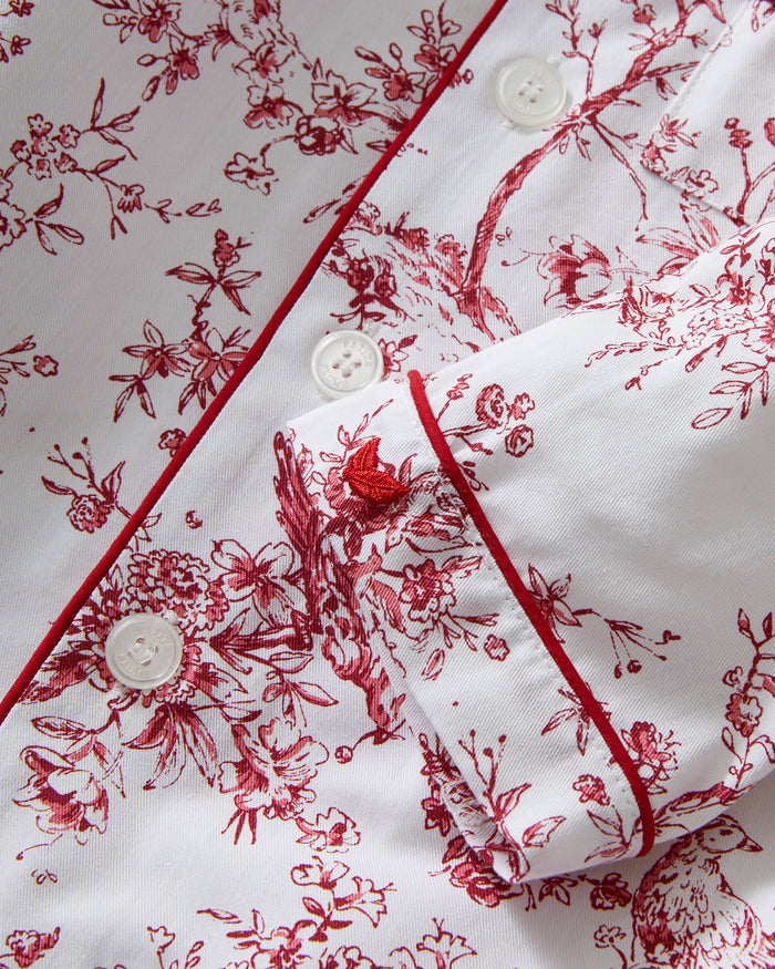The Kid's Twill Pajama Set in Red Timeless Toile features a white base with red toile print, long-sleeve button-up top with front pocket, matching pants, and red piping accents.