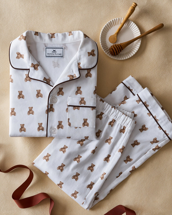 Kid's Twill Pajama Set in Teddy Tales: white long-sleeve, button-up pajamas with pants, featuring brown teddy bear print, dark piping along edges and chest pocket.
