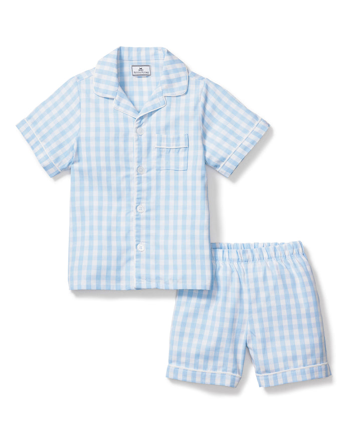 The Kid's Twill Pajama Short Set in Light Blue Gingham features a button-up short-sleeve top with a chest pocket and matching elastic-waist shorts in a classic gingham check pattern.
