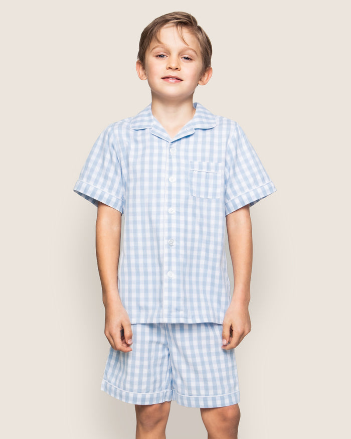 The Kid's Twill Pajama Short Set in Light Blue Gingham features a button-up short-sleeve top with a chest pocket and matching elastic-waist shorts in a classic gingham check pattern.