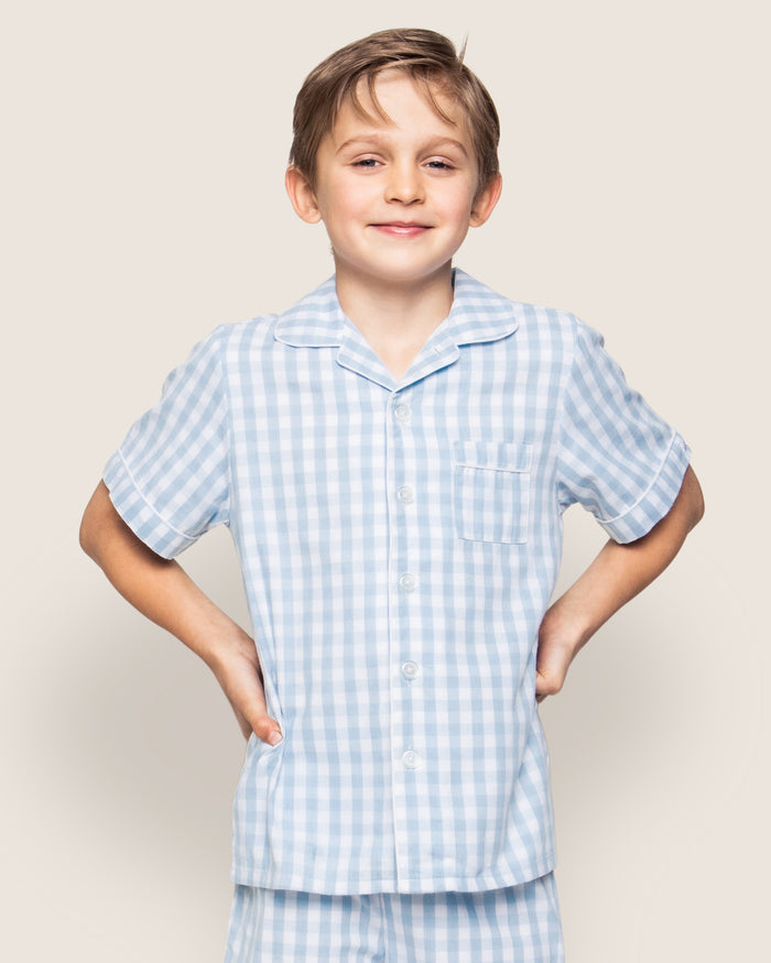 The Kid's Twill Pajama Short Set in Light Blue Gingham features a button-up short-sleeve top with a chest pocket and matching elastic-waist shorts in a classic gingham check pattern.