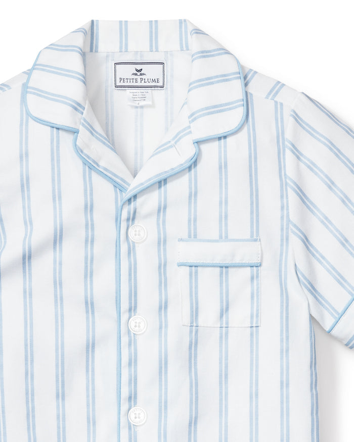 A close-up of the Kids Twill Pajama Short Set in Periwinkle and White Stripe by Petite Plume, featuring a collared top with white buttons and a chest pocket—crafted for cozy, relaxing evenings.