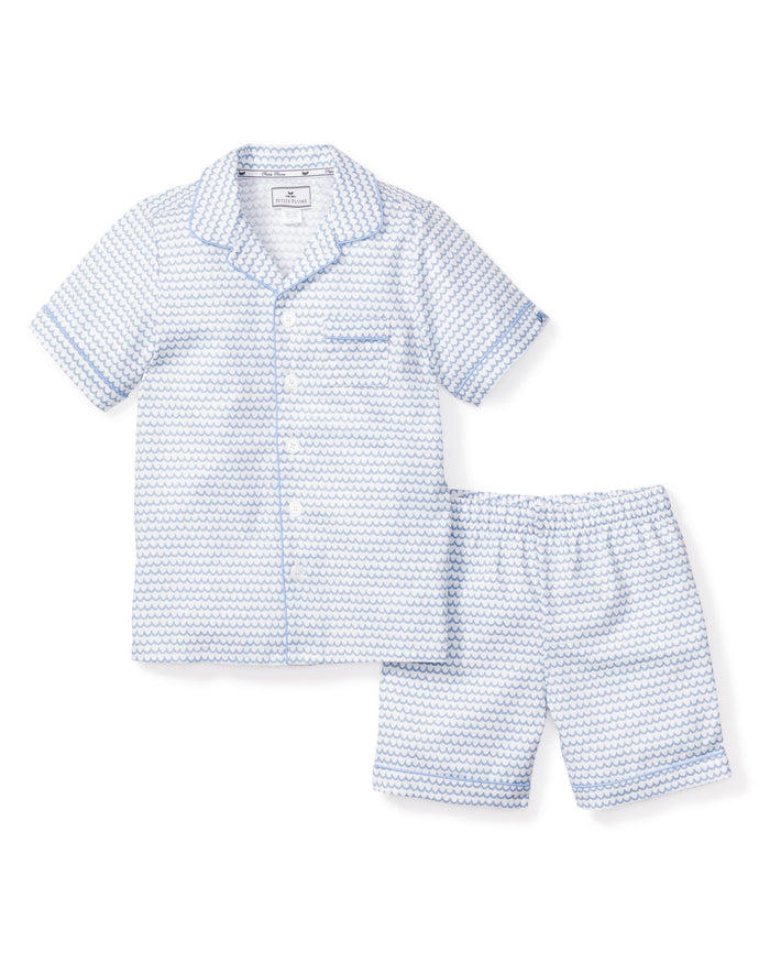 Explore the Kids Twill Pajama Short Set in La Mer by Petite Plume: a light blue patterned short-sleeve set made from premium cotton, featuring a button-up top with a collar and chest pocket, plus matching elastic waistband shorts for comfort and style.