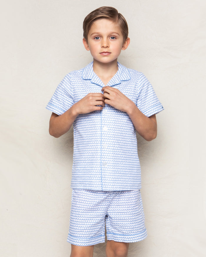 A young boy models Petite Plumes Kids Twill Pajama Short Set in La Mer, made from high-quality cotton, against a plain background, looking directly at the camera with a neutral expression.